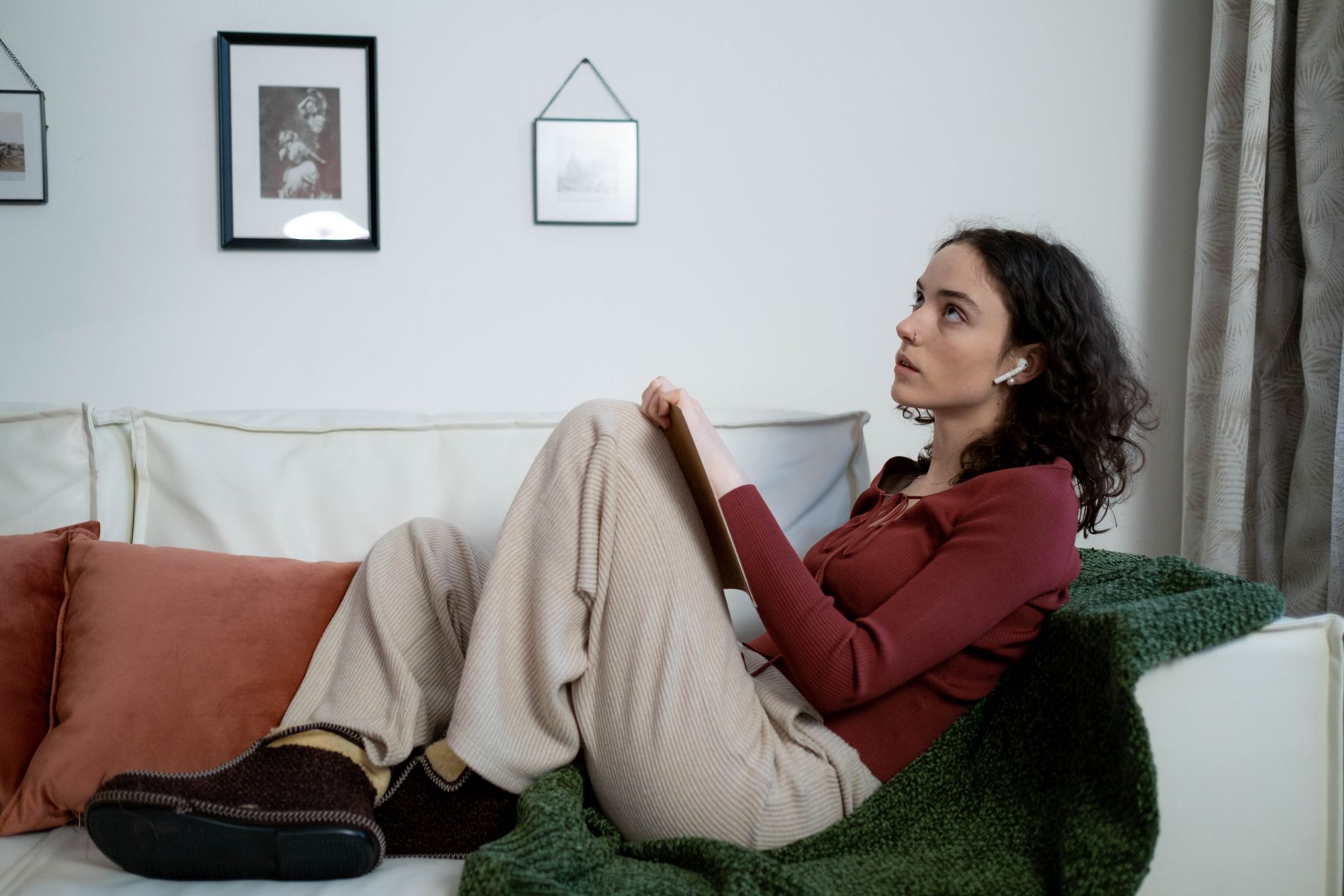 A woman pausing thoughtfully with a notebook on her lap