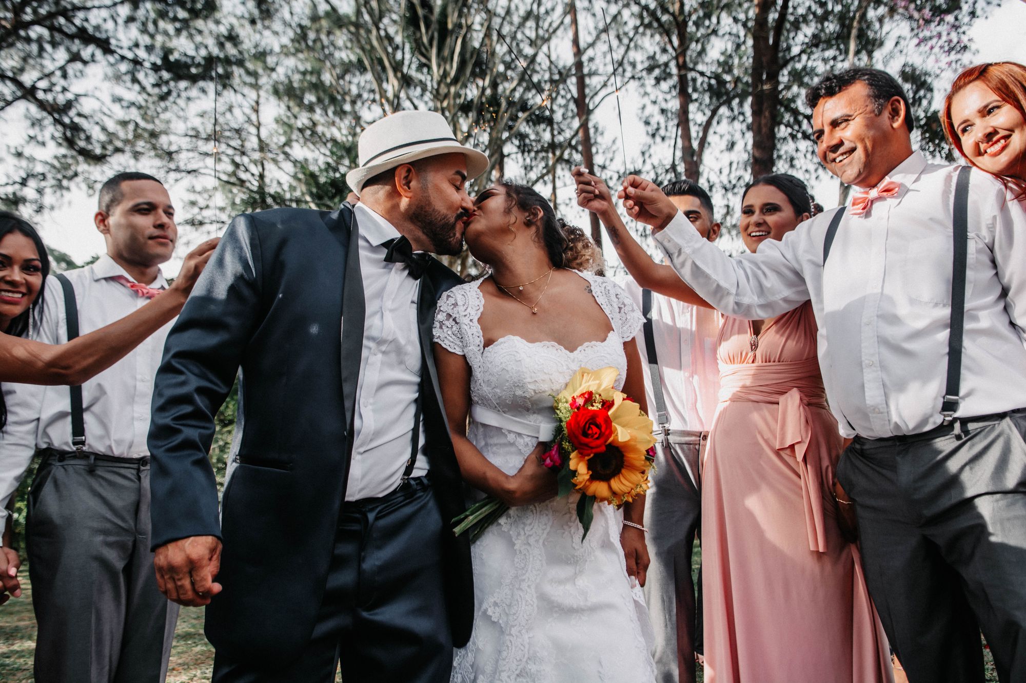 Wedding guests cheering as a newly married couple share a kiss